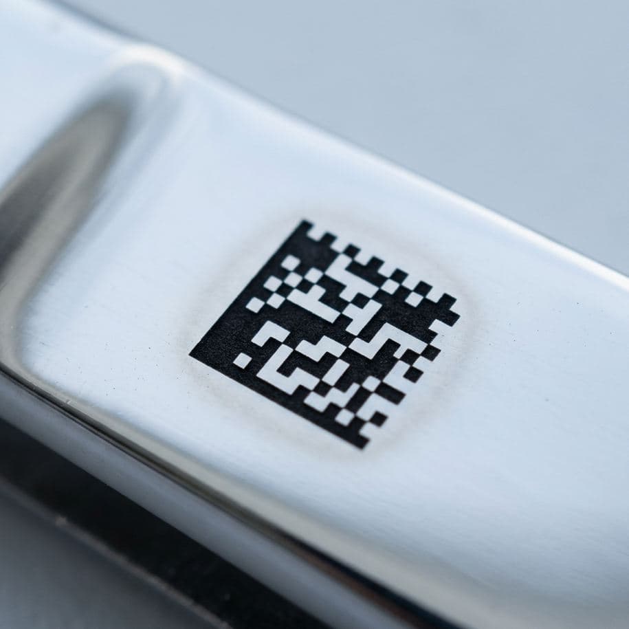 Laser-annealed 2D Data Matrix code on a polished medical-grade stainless steel surface — deep black, flush with the substrate, no material removal.